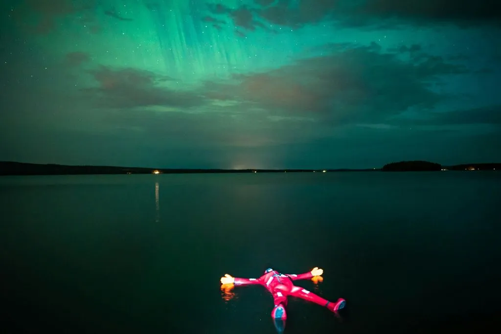 Finlandia: Vista sul lago dell'aurora boreale con tuta galleggiante