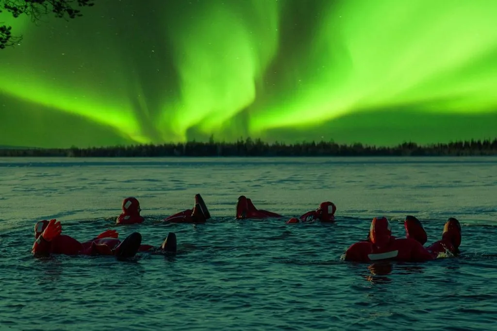 Finlandia: Vista sul lago dell'aurora boreale con tuta galleggiante